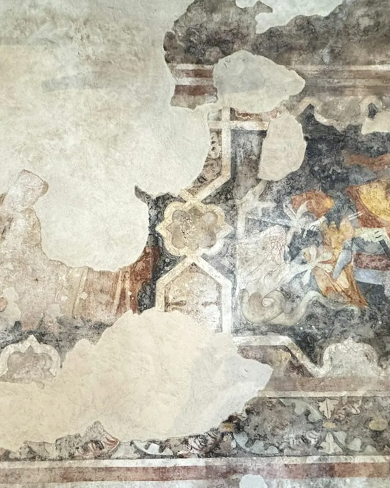 Detalle de una pintura mural con la capa de color desgastada, lagunas en el enlucido y manchas de humedad