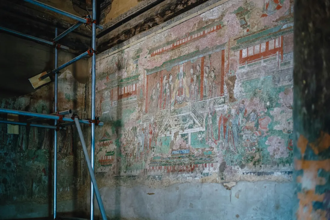 Pintura mural antigua sobre un muro enlucido con un andamio metálico montado delante durante los trabajos